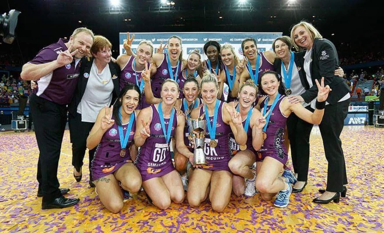 Queensland Firebirds squad celebrating an ANZ Championship premiership with the trophy and confetti.